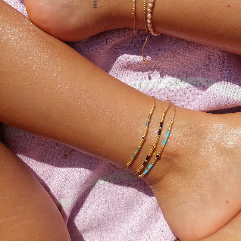 Add a pop of subtle color to your style with our Gleam Beads Adjustable Anklets. Featuring delicate colorful and gold beads on a silky cotton string, these adjustable anklets are perfect for layering, with five colors available to create your unique combinations.